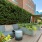 a deck with chairs and plants on it by a building