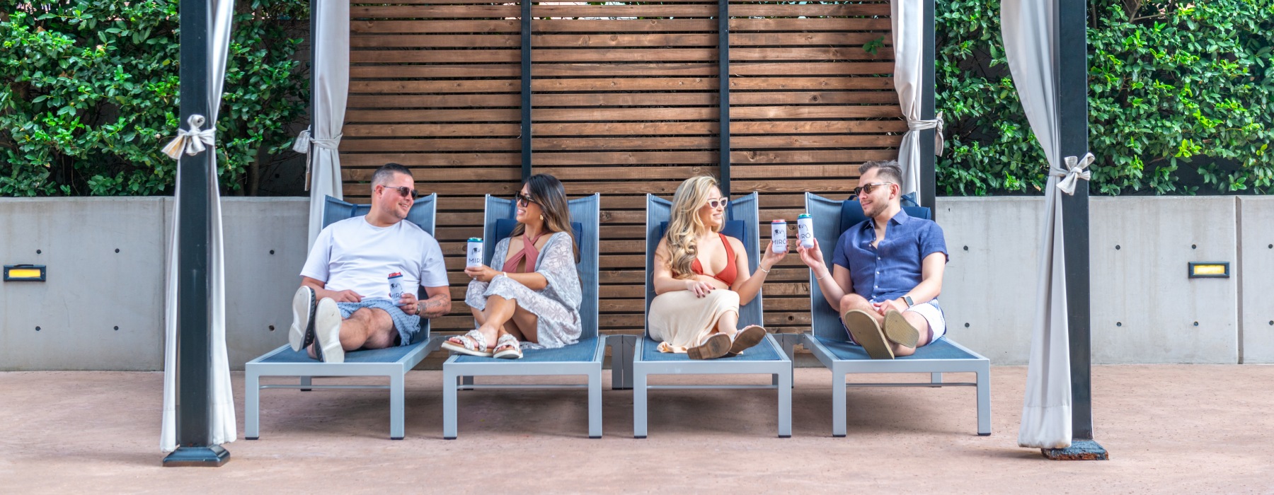 four people sitting on chairs relaxing under a cabana